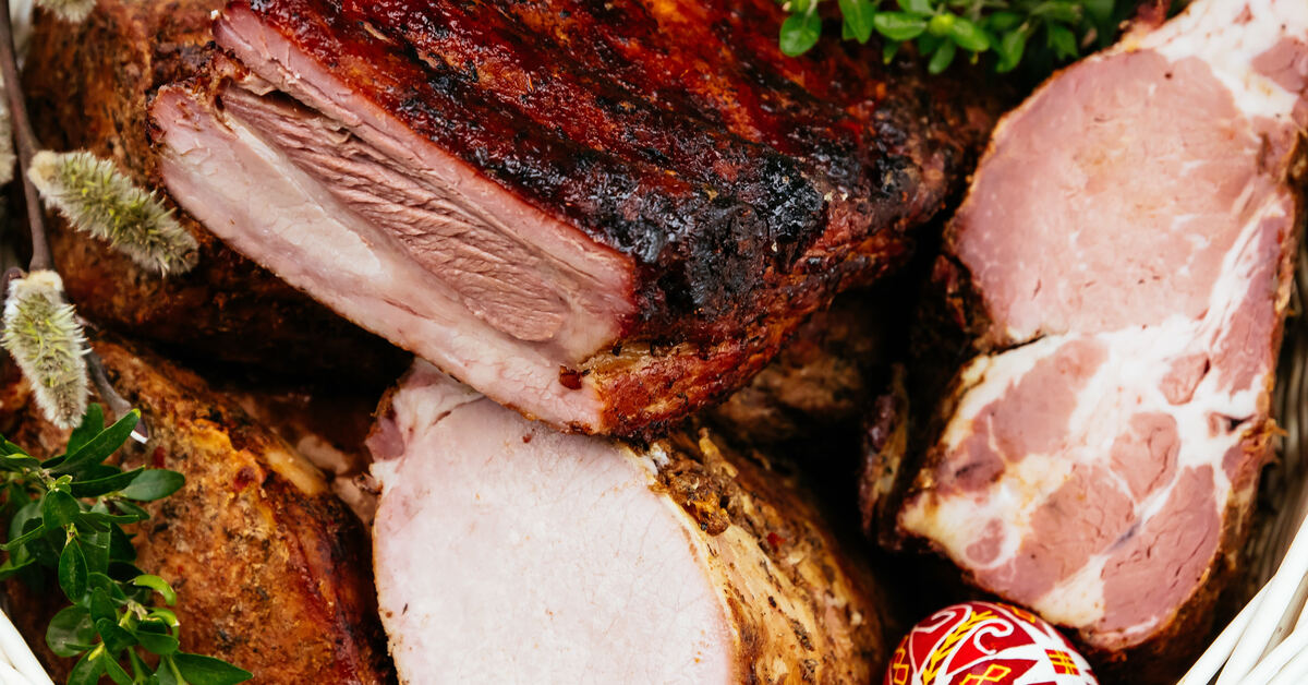 Smoked meat served in a wooden gift basket. There are three different types of meat that are sliced evenly.